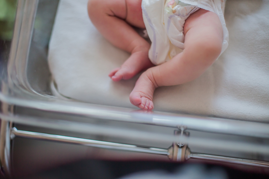 Legs of a newborn baby lying in a couveuse. The child has just been born and is in the hospital clinic with his mother. Natural childbirth. Cesarean section.